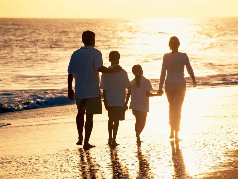 family of 4 walking on the beach at sunset
