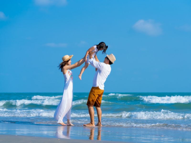 family of 3 playing on the beach